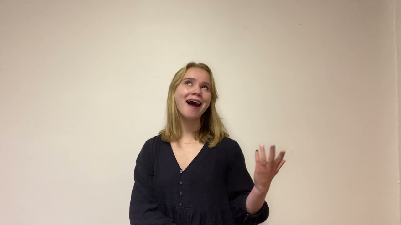 Charlotte Kearns stands against a white wall, making a playful face