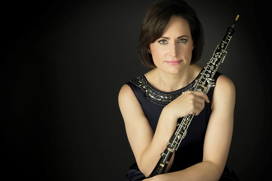 Erin Hannigan in a black dress elegantly holds a clarinet
