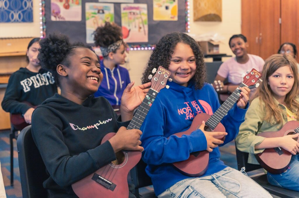 A group of young girls joyfully playing ukuleles together