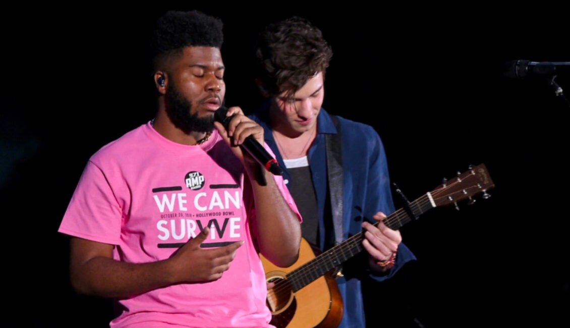 Two men in pink shirts performing a duet on stage