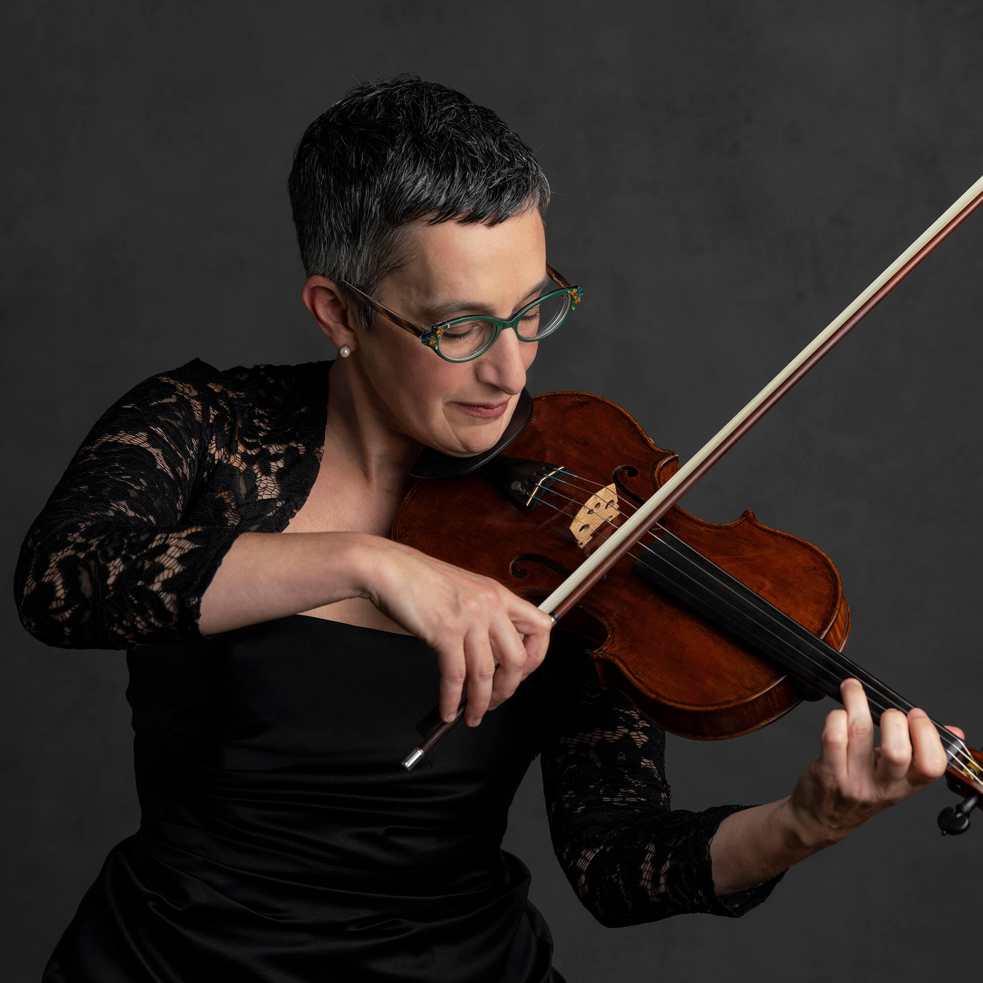 Lorien Benet Hart against a black background playing the violin